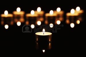15220569-one-burning-tea-candle-in-front-of-many-burning-tea-candles-on-a-black-mirror